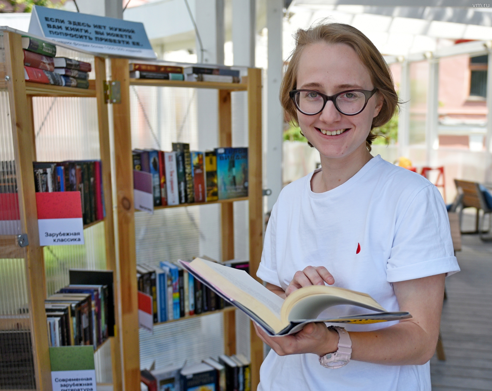 Читательница Екатерина Фадейкина листает книгу из фонда летней читальни Центральной библиотеки имени Н. А. Некрасова